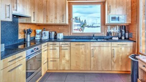 A modern kitchen with wooden cabinets, a built-in oven, and a window with a snowy view. - Chalet, wifi, ski-in/ski-out & foot of the slopes, sauna, terrace, balcony, fireplace or stove (Les Collons)