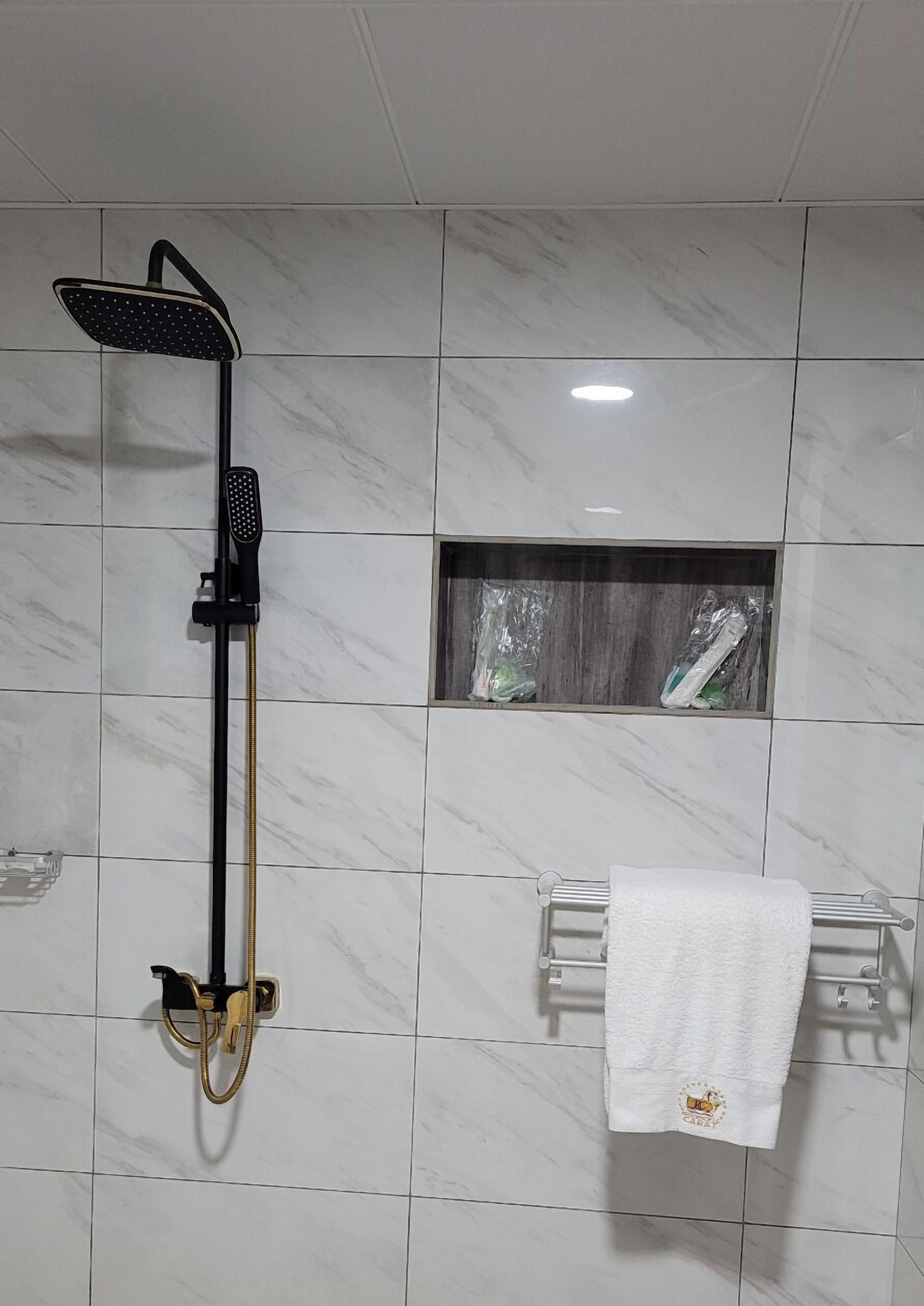 Un baño con ducha, toallero y un pequeño ventanal.
