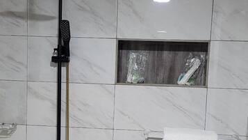 Un baño con ducha, toallero y un pequeño ventanal.
