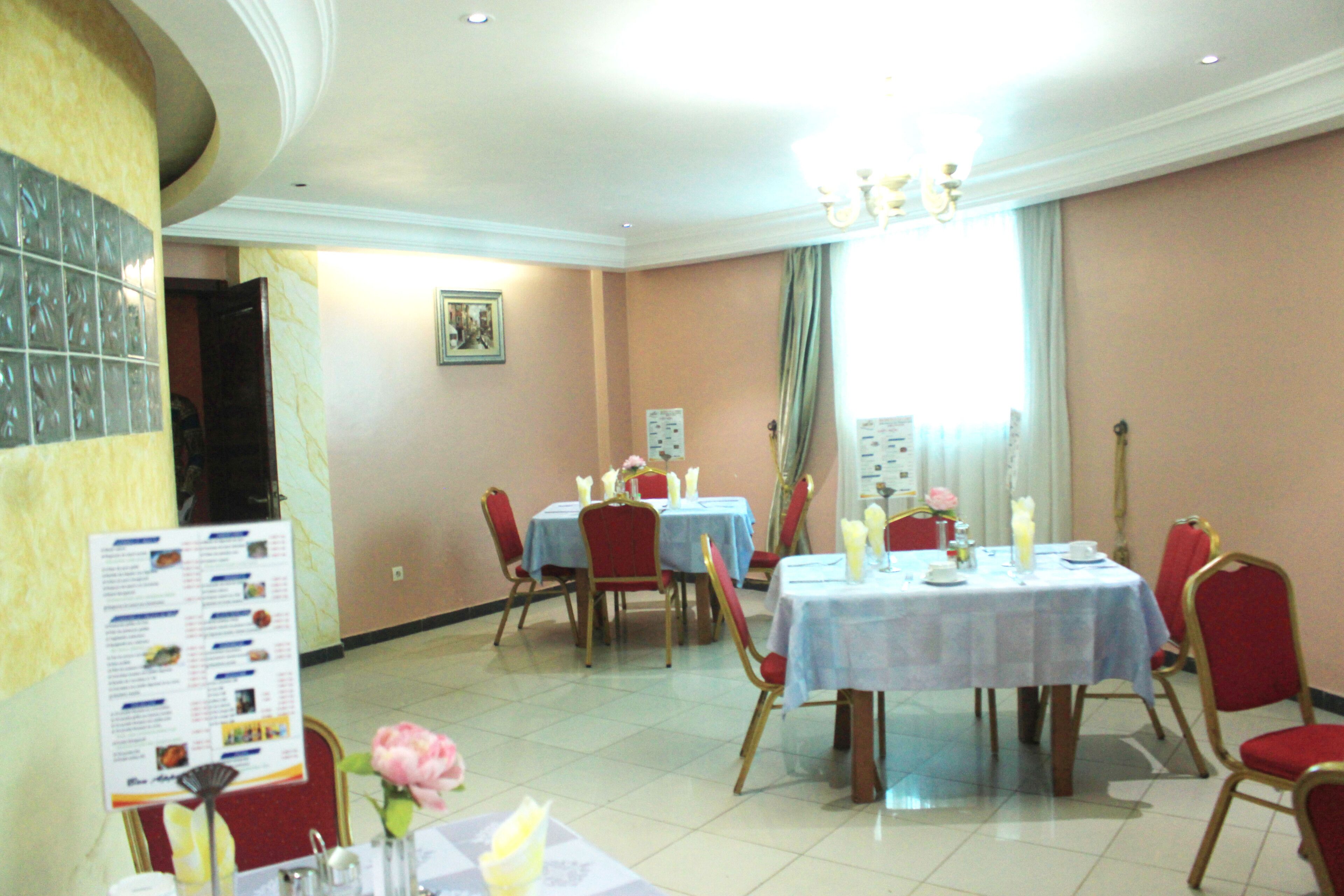 A dining area with tables set for service, red chairs, and a chandelier.