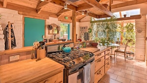 Una cocina rústica con vigas de madera, una estufa a gas y diversos utensilios de cocina.