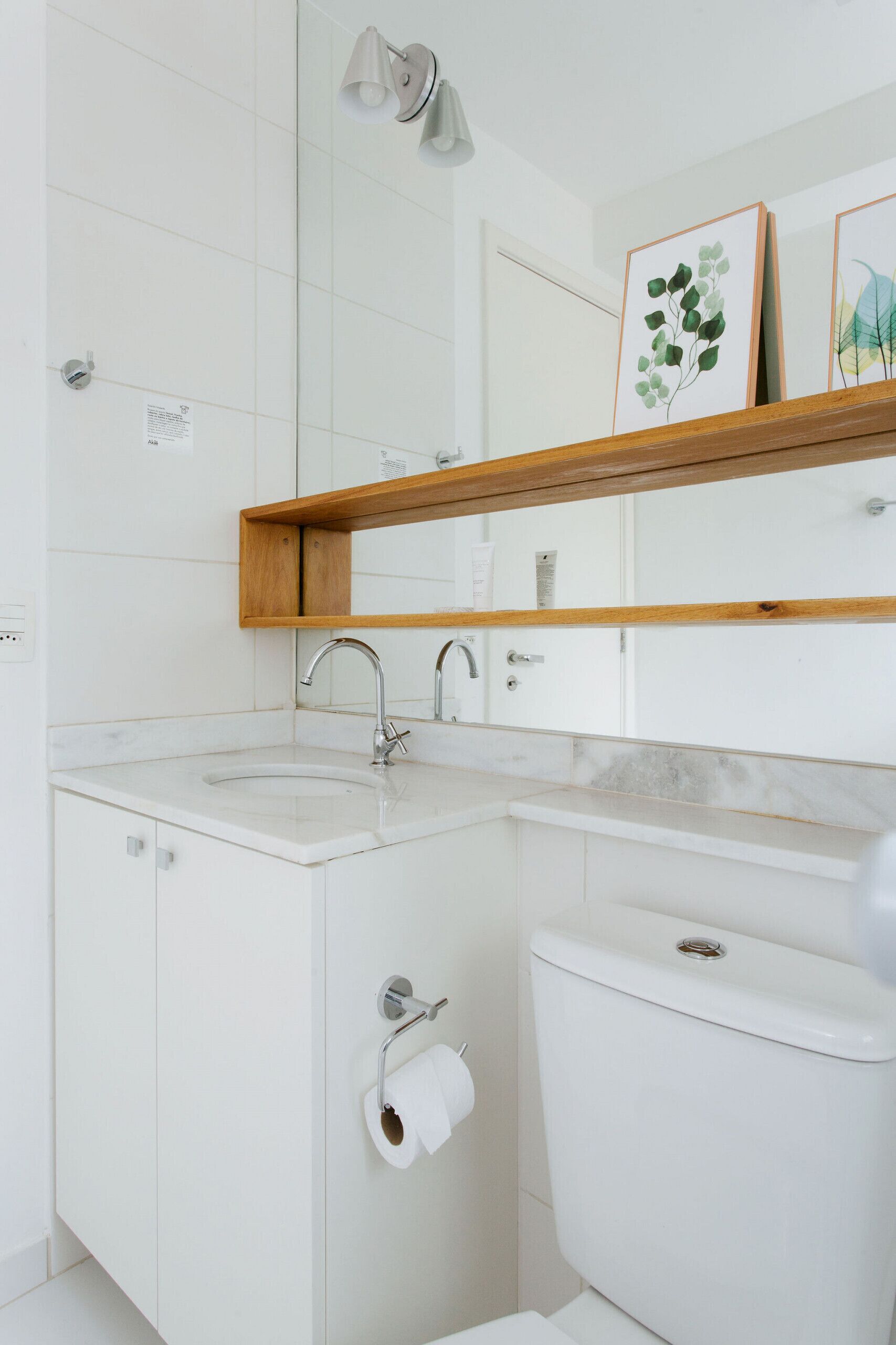 Ein modernes Badezimmer mit einem weißen Waschbecken, einer Toilette und einem Spiegel über dem Waschbecken.