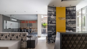 Un hall d’entrée moderne comprenant un comptoir d’accueil, un espace détente et un mur orné de photographies de paysages urbains.