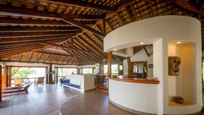 Un hall d’entrée spacieux avec un plafond haut, un comptoir d’accueil incurvé et un espace détente avec des fauteuils et un canapé.