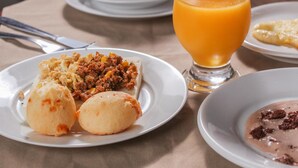 Et morgenbord med mad på en tallerken, et glas appelsinjuice og en kop kaffe på et bord.