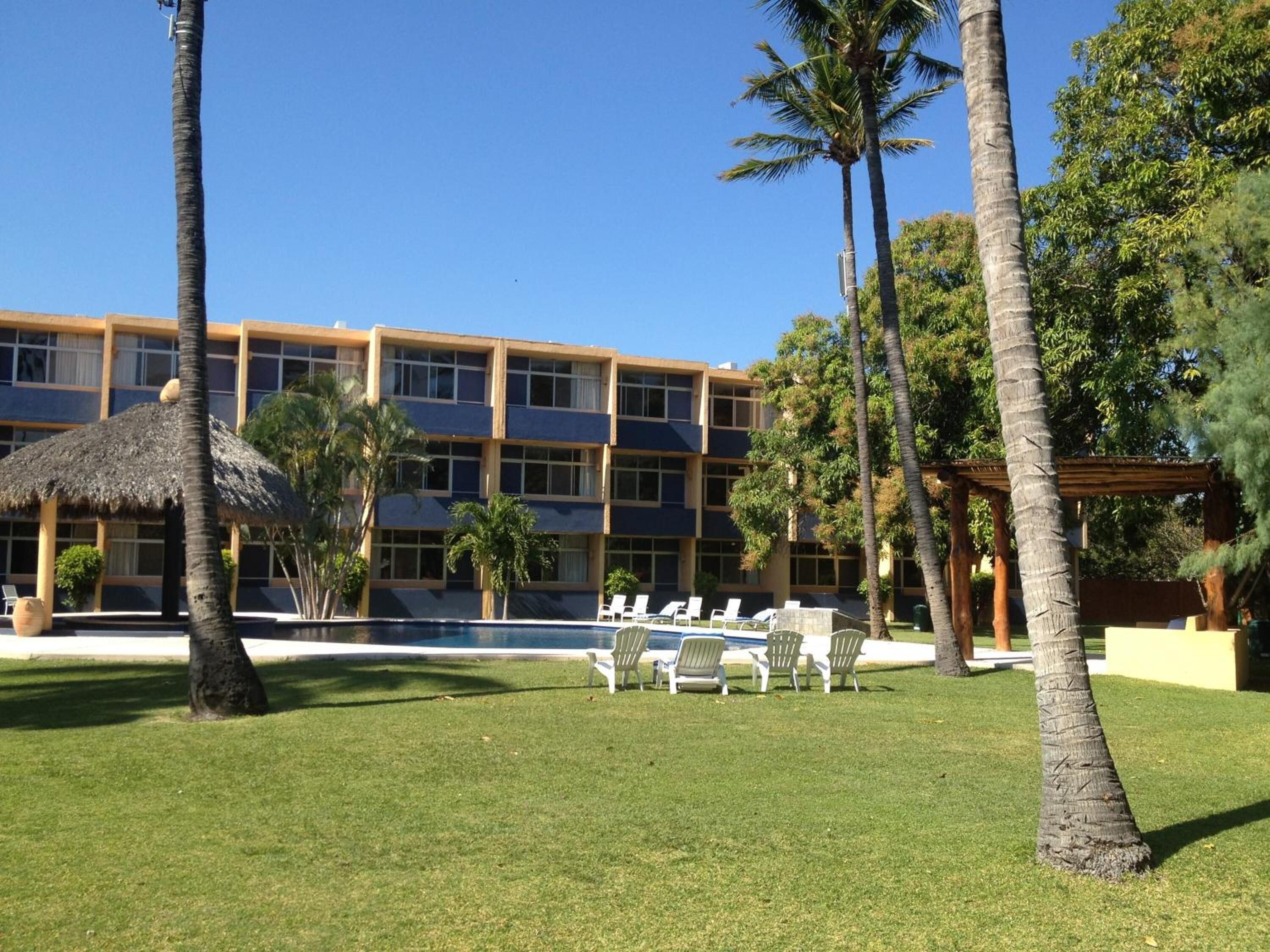 Un hotel con piscina, palmeras y sillas de descanso.