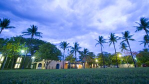 A hotel with a courtyard, palm trees, and a building with a lighted entrance. - Hotel Calli (Tehuantepec)