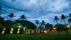 A building with a symmetrical facade, surrounded by a well-maintained lawn and palm trees. - Hotel Calli (Tehuantepec)