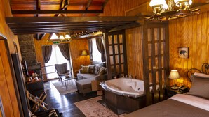 A room with a large bathtub, a sofa, a chair, and a desk with a lamp. - The Swanpark Hotel (Sile)