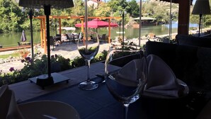An outdoor dining area with tables and chairs, a view of a lake, and a gazebo. - The Swanpark Hotel (Sile)