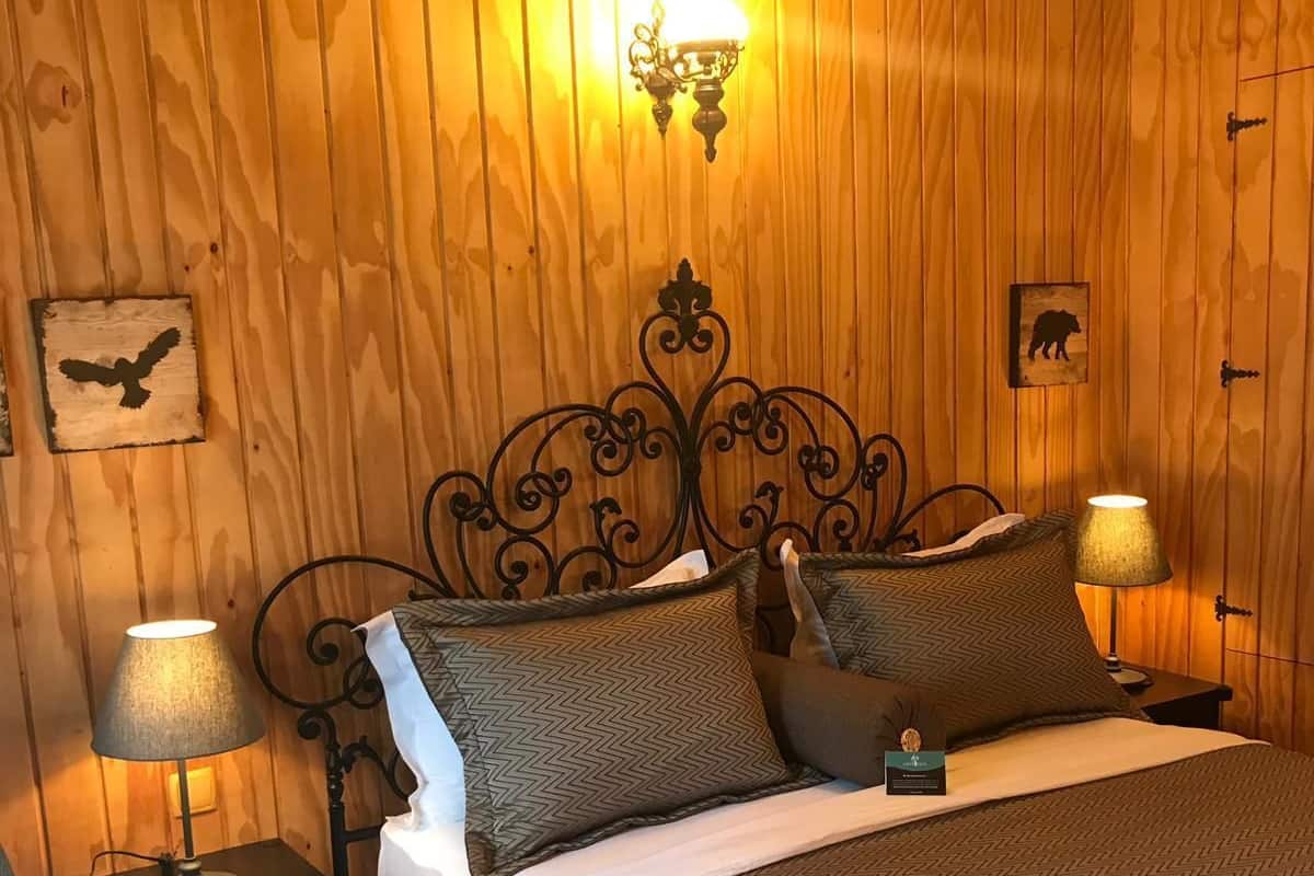 A wooden-paneled room with a bed, two bedside lamps, and wall decorations including an eagle and a bear.