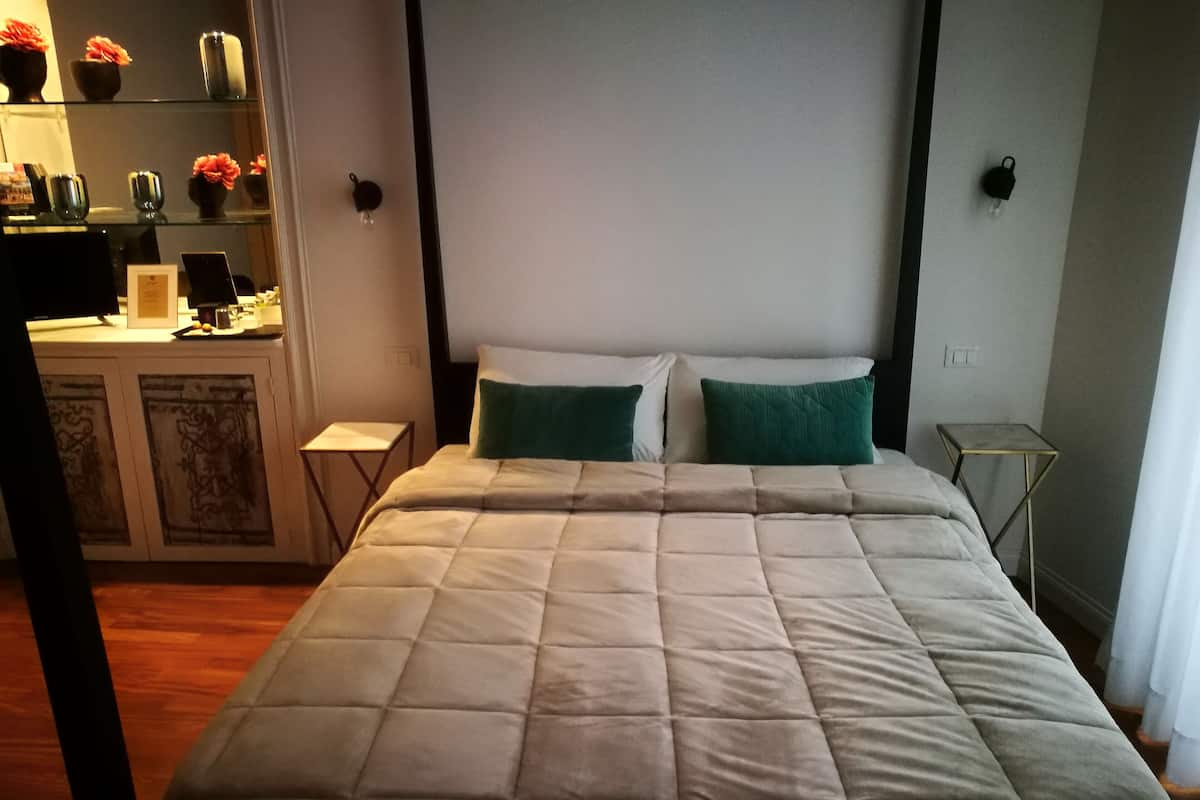 A neatly made bed with a quilted duvet, a bedside table, and a small lamp.