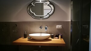 Un baño moderno con un lavabo ovalado grande, un espejo con marco circular y un perchero para toallas.