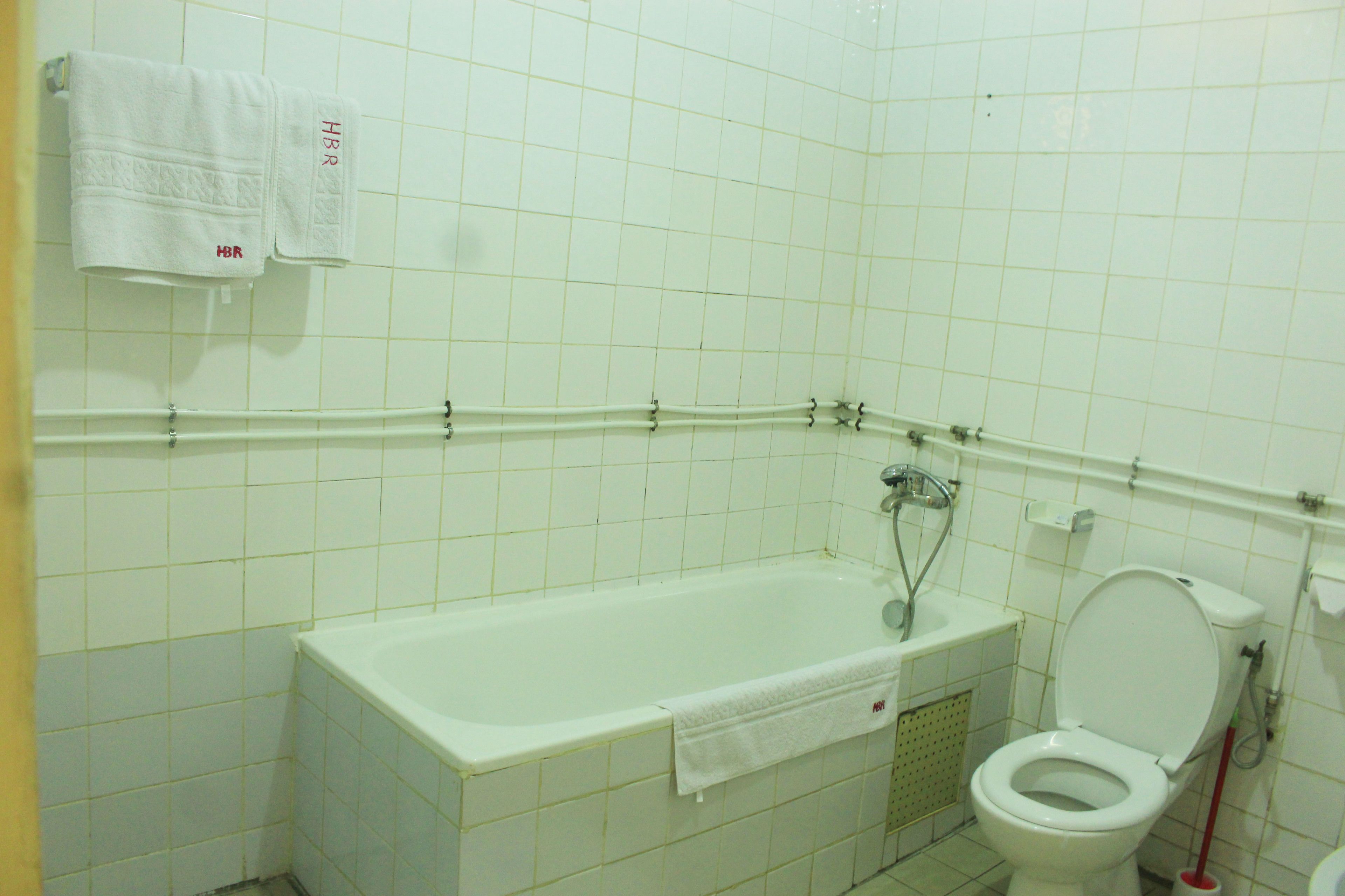 A bathroom with a bathtub, toilet, and a towel rack with towels.
