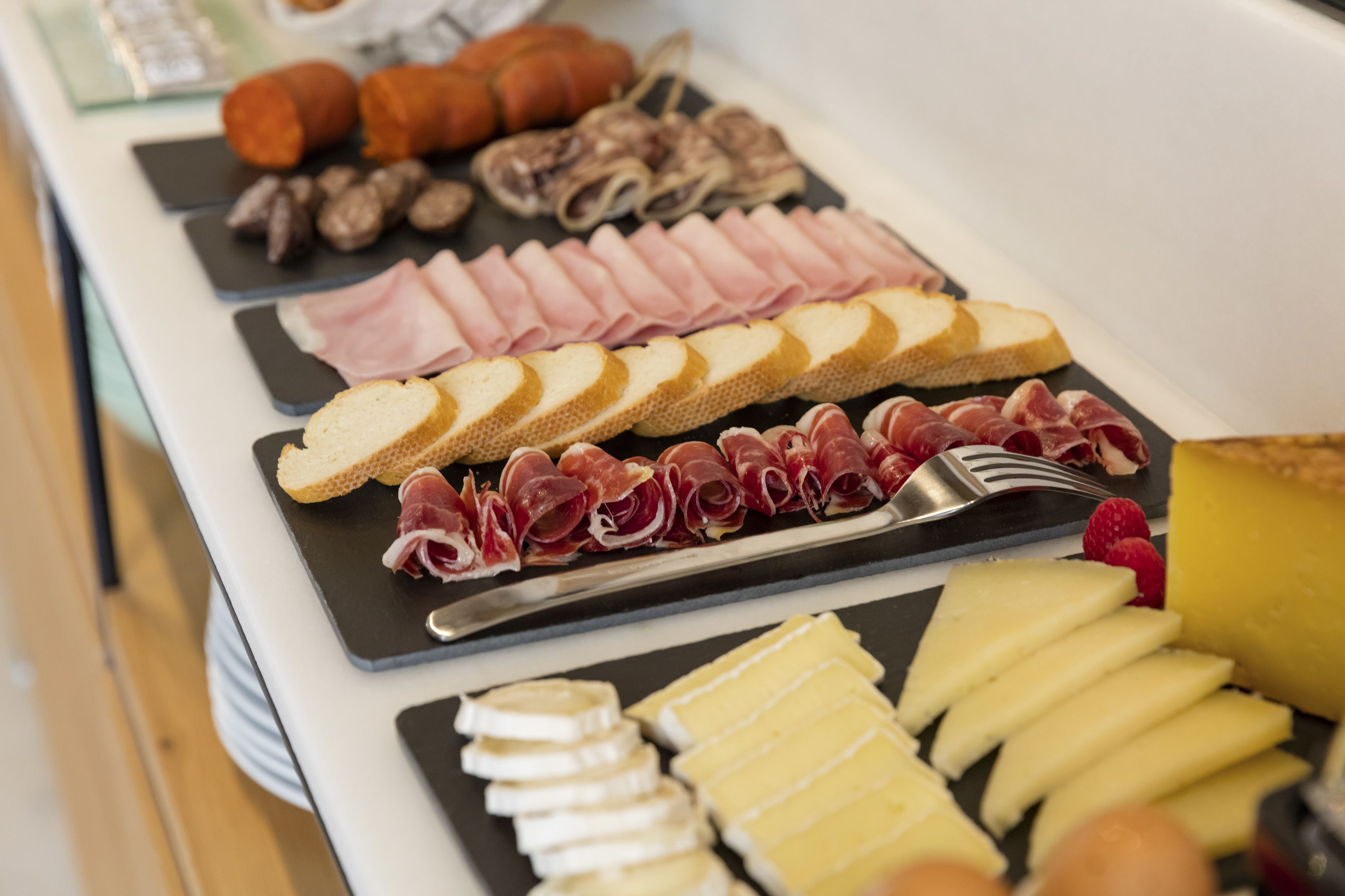 Una tabla de embutidos con diferentes carnes, quesos y pan.