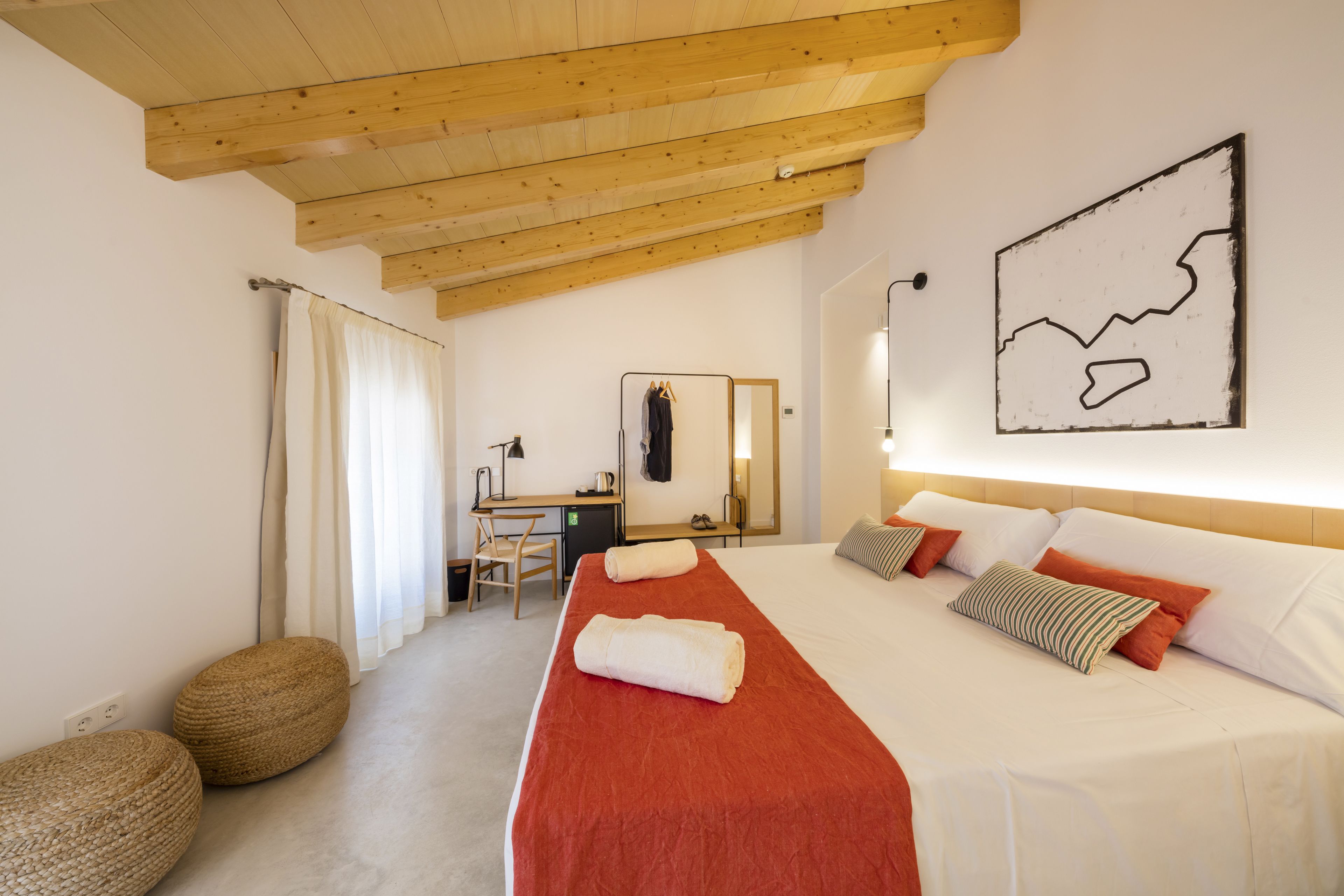 Una habitación de hotel con cama, escritorio, silla y un espejo grande.