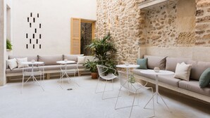 Ein modernes Interieur mit Steinwand, einer Sofagarnitur und weißen Metallstühlen sowie Tischen.