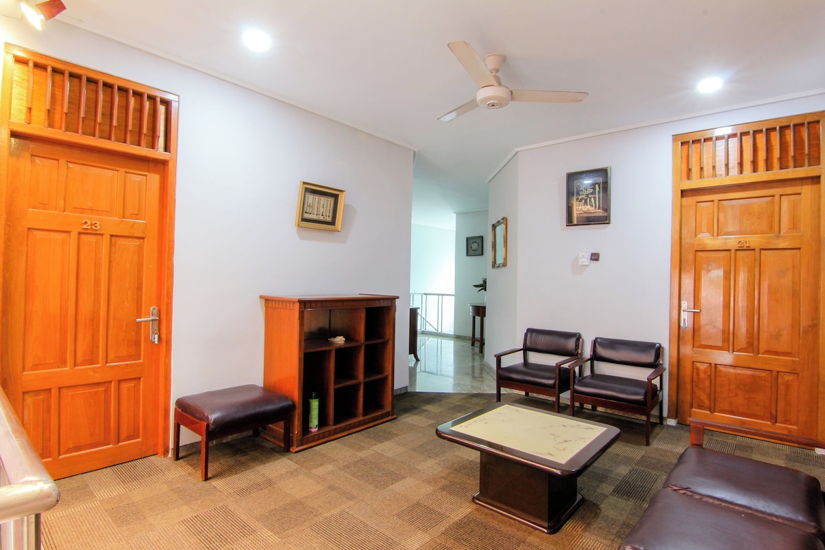 A room with a billiards table, two armchairs, a wooden cabinet, and a bench.