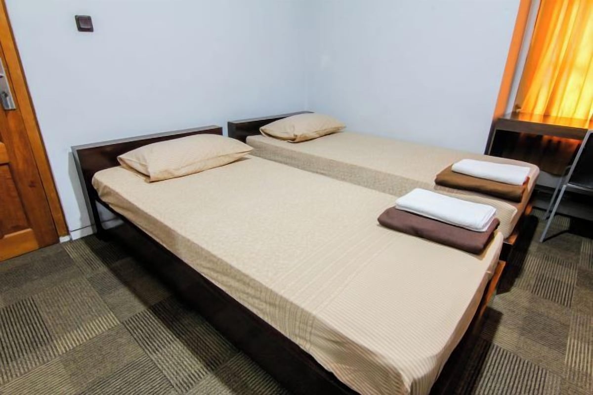 A twin room with two single beds, a wooden door, and a small table with a chair.