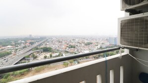 Een balkon met uitzicht over de stad, een airconditioner en een hekwerk.