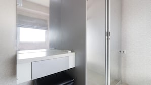 Een moderne badkamer met een douchecabine van glas, een witte wastafel en een behang met een patroon.