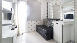 Een moderne, goed verlichte kamer met een zwarte bank, een wit bureau en een grote spiegel.