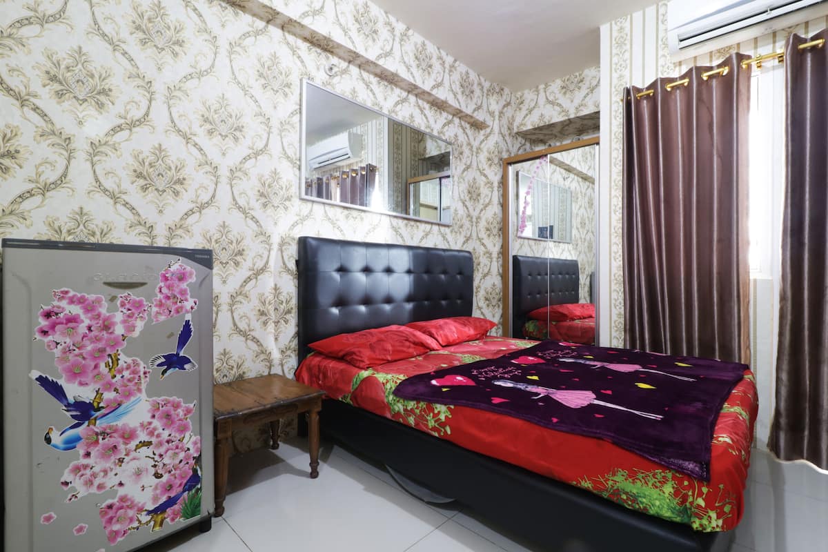 Een slaapkamer met een groot bed, twee nachtkastjes, een dressoir en een spiegel aan de muur.