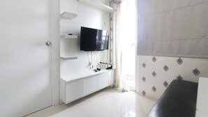 Een moderne kamer met een witte entertainmentkast, een flatscreen televisie en een bankje.