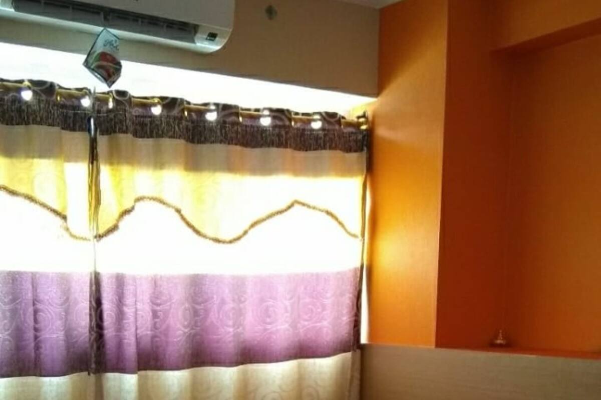 A bedroom with a bed, curtains, and an air conditioning unit.