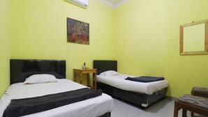 Ein Zimmer mit zwei Betten, einem kleinen Tisch, einer Klimaanlage und einem Bild an der Wand.