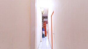 A narrow hallway with white tiled floors and orange doors. - Techno Inn (Makassar)