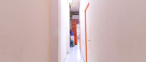 A narrow hallway with white tiled floors and orange doors.