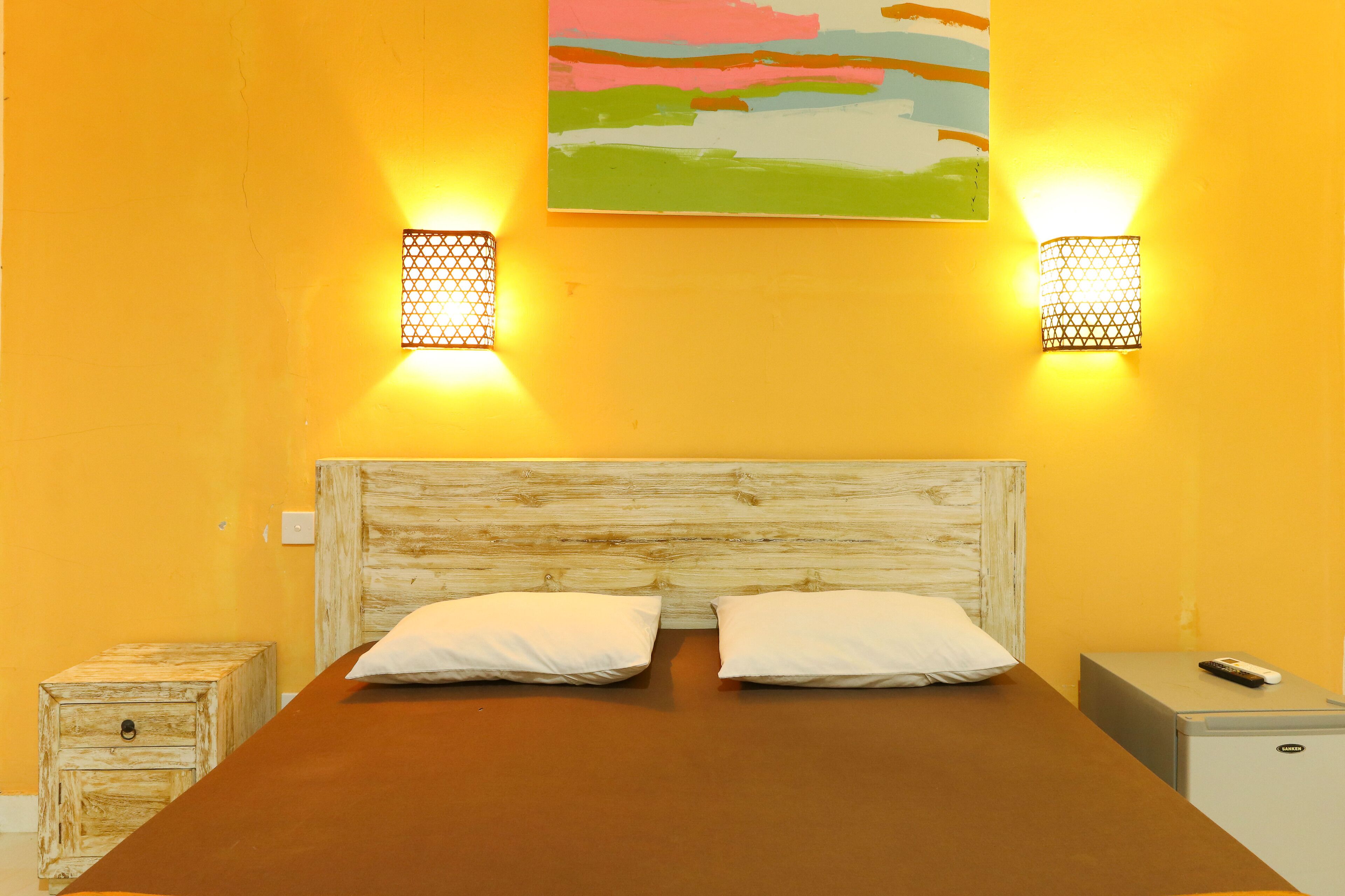 A room with a wooden headboard bed, two bedside tables, and a painting on the wall.