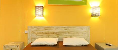 A room with a wooden headboard bed, two bedside tables, and a painting on the wall.