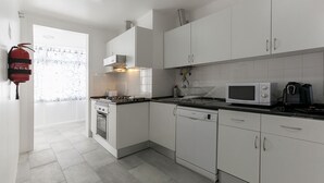 Une cuisine moderne avec des meubles blancs, une cuisinière à gaz, un four à micro-ondes et un lave-vaisselle.