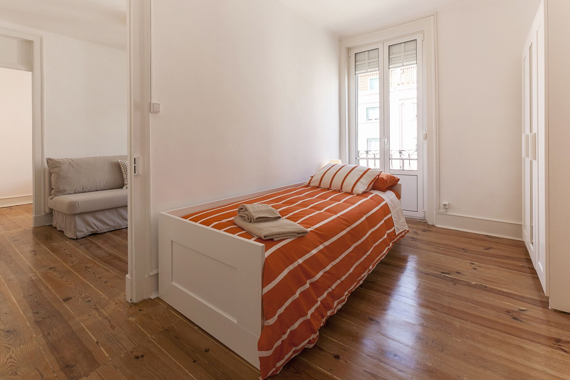 A bedroom with a bed, a sofa, and a window.