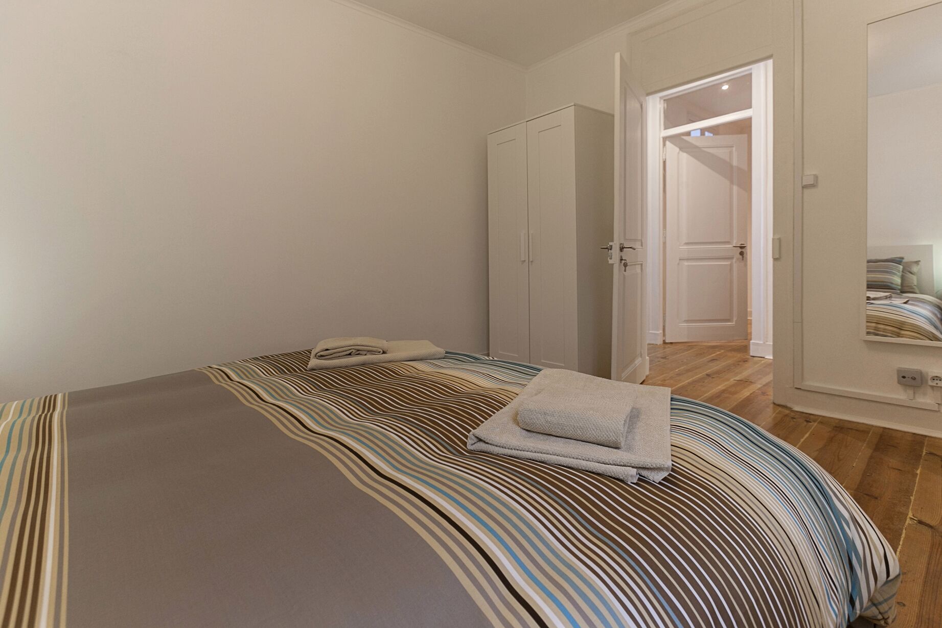 Ein Schlafzimmer mit einem Bett, einem Kleiderschrank und einer Tür zu einem weiteren Raum.