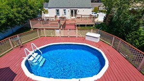 A rectangular swimming pool with a wooden deck and a metal ladder. - Great Family Times In this lovely Cape with Resort style backyard (Massapequa)