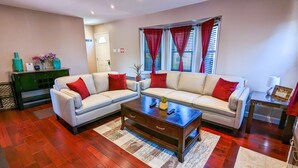 A living room with a white sofa, red cushions, a wooden coffee table, and a red and white striped rug. - Great Family Times In this lovely Cape with Resort style backyard (Massapequa)