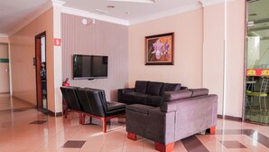 A hotel lobby with a sofa, chairs, a TV, and a framed picture on the wall. - Canada Hotel (Rio Verde)