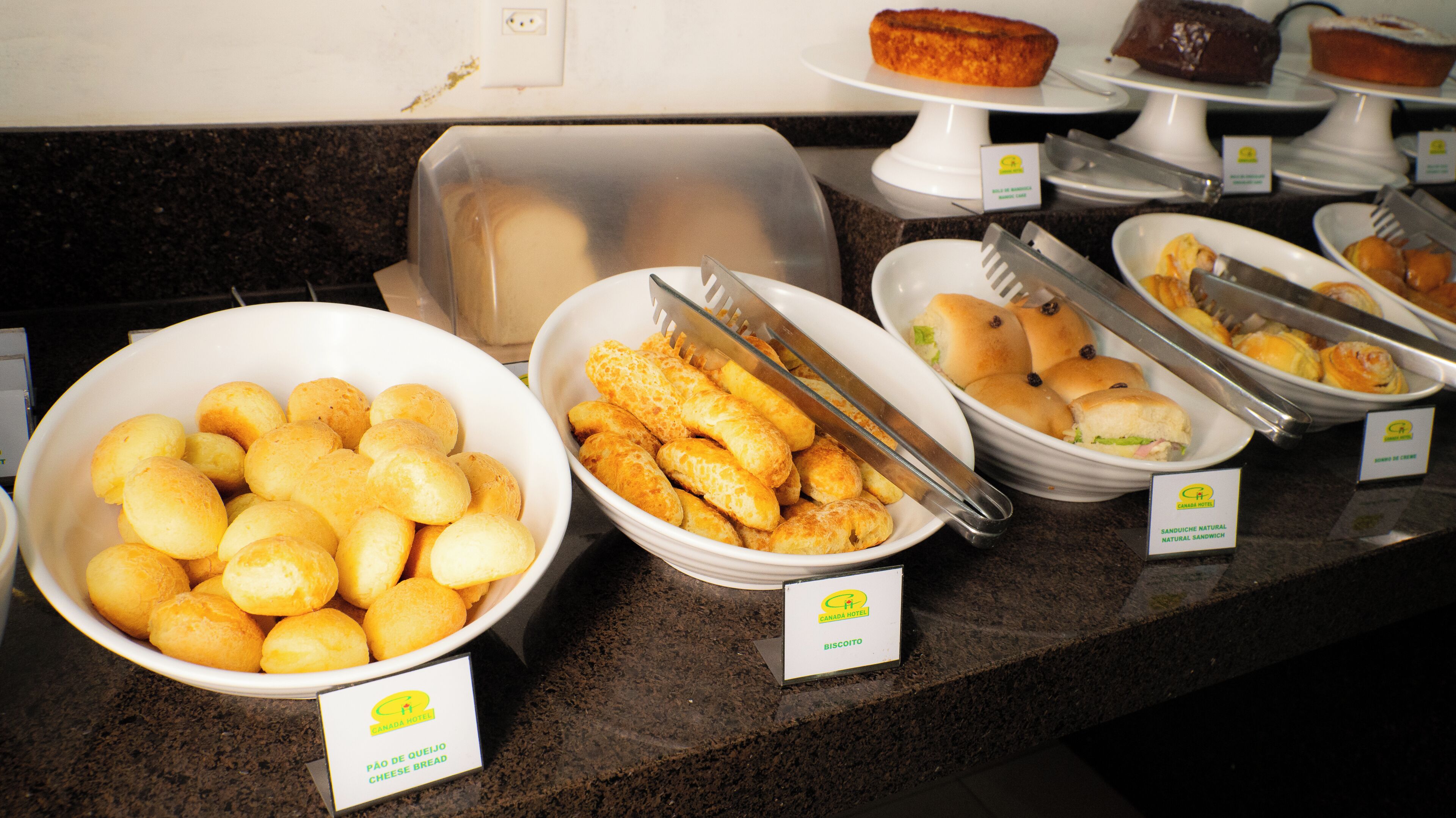 A buffet with various food items including cheese bread, sandwiches, and pastries.