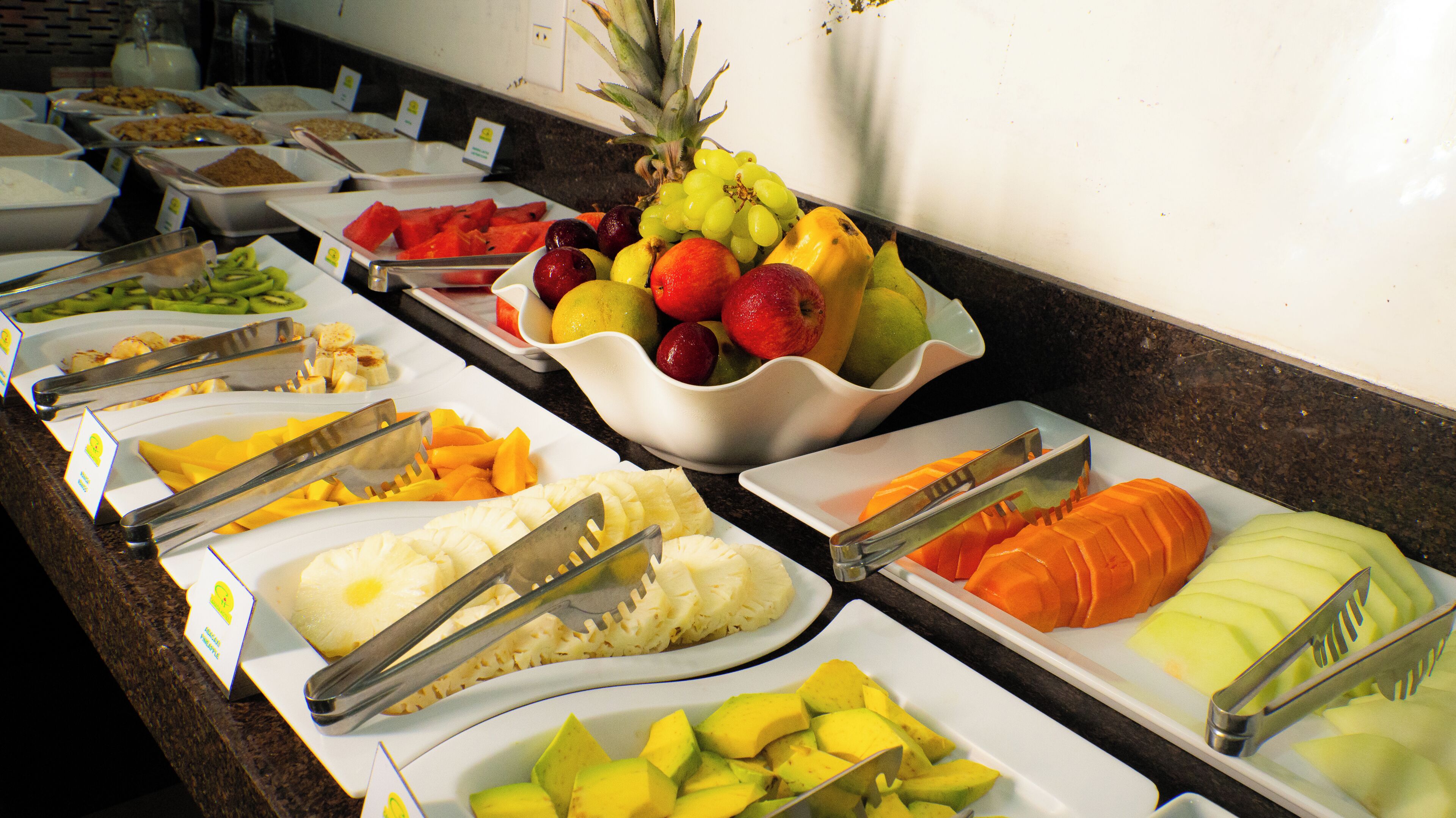A buffet with various fruits and vegetables, including pineapple, mango, and avocado.