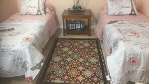 A room with two beds, each with a Paris-themed duvet and pillow, a small wooden nightstand with a vase of flowers, and a patterned rug. - Perfect getaway! Newly remodeled waterfront suite. (North Port)