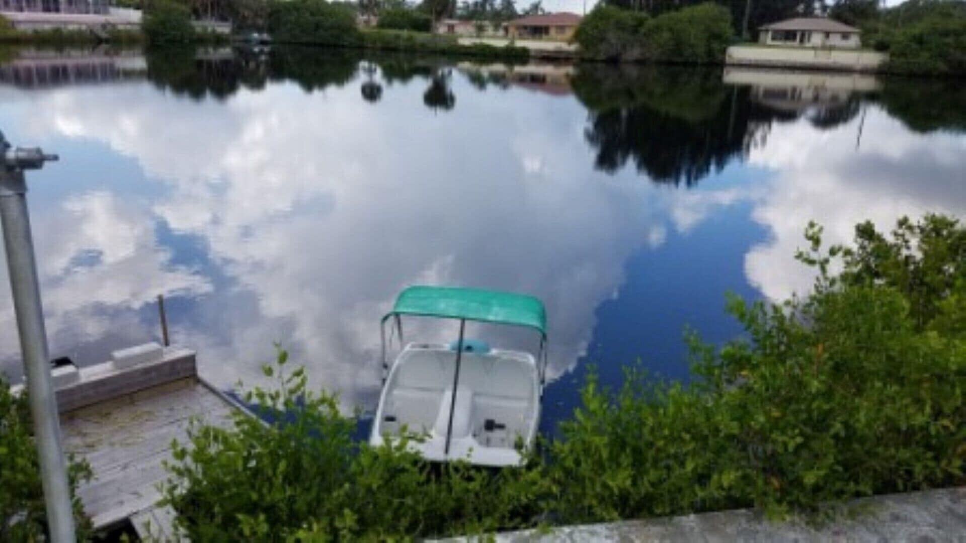 Un bateau était amarré sur un lac paisible, dont les eaux reflétaient les nuages et les bâtiments.