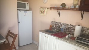 A kitchen with a microwave, refrigerator, sink, and a small countertop with a kettle and a bottle. - Perfect getaway! Newly remodeled waterfront suite. (North Port)