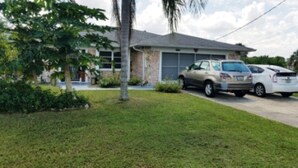 A residential house with a garage, two cars parked in front, and a well-maintained lawn. - Perfect getaway! Newly remodeled waterfront suite. (North Port)
