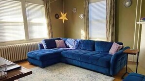 Ein Wohnzimmer mit einem blauen Ecksofa, einem gemusterten Teppich und einer Stern-Dekoration an der Wand.
