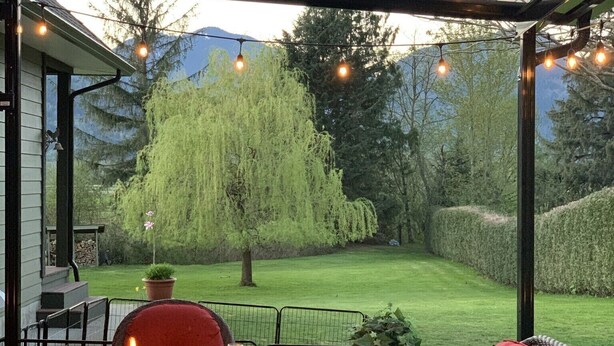 Une terrasse extérieure avec des meubles en osier, un foyer et des guirlandes lumineuses.