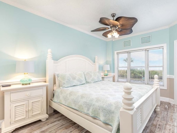 A bedroom with a bed, nightstands, a ceiling fan, and a window with blinds.