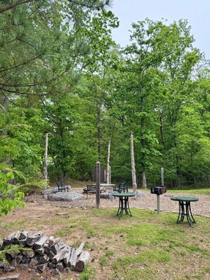 A campsite with picnic tables, benches, and a fire pit.